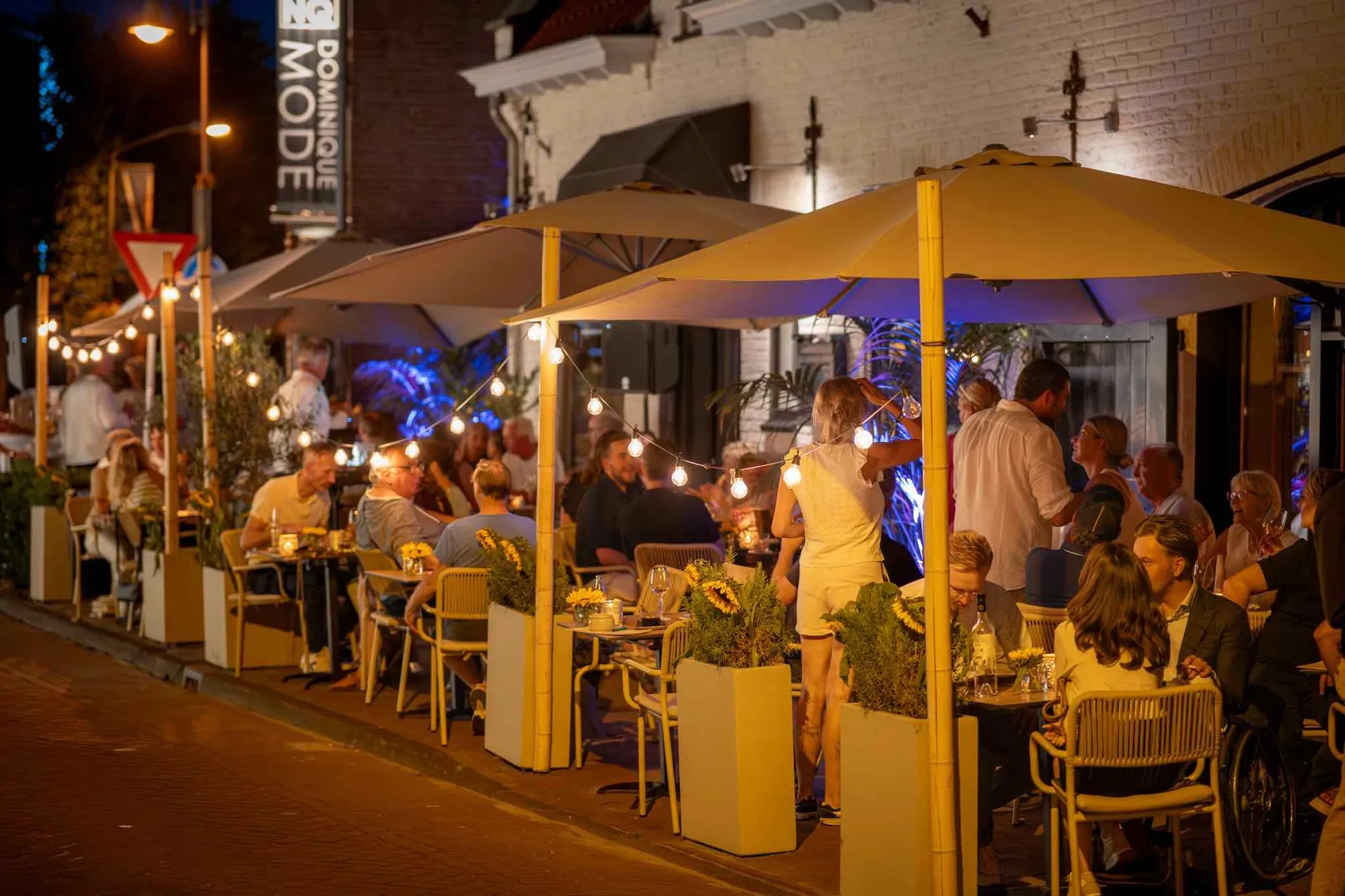 De gevel van Blend in de avond, het terras vol en de lampen aan